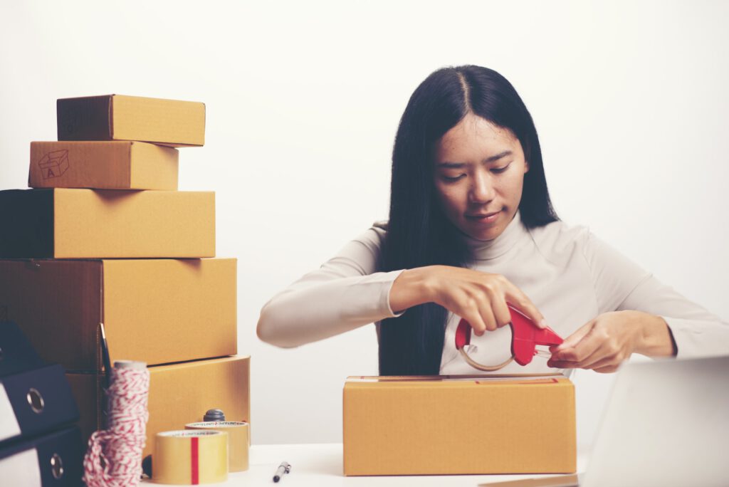 Female hands packing box at warehouse, online marketing concept